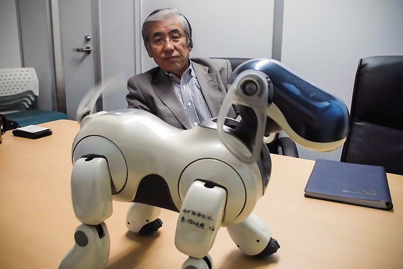 Норімацу Нобуюкі дивиться на робота AIBO, махає хвостом